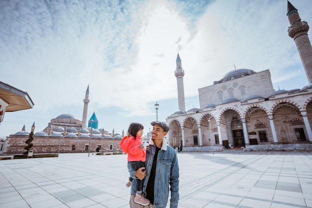 Vader en zijn kleine meid lopen over het plein in konya, turkije, genietend van de prachtige islam