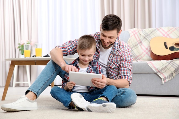 Vader en zijn zoon met tabletcomputer thuis