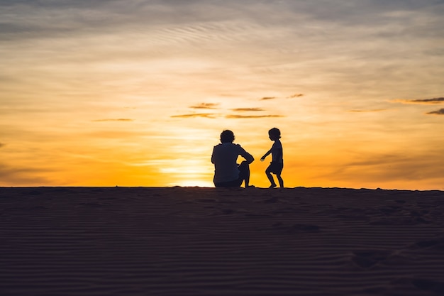 Vader en zoon bij de rode woestijn bij dageraad. Reizen met kinderen concept.