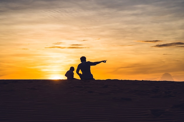 Vader en zoon bij de rode woestijn bij dageraad. Reizen met kinderen concept