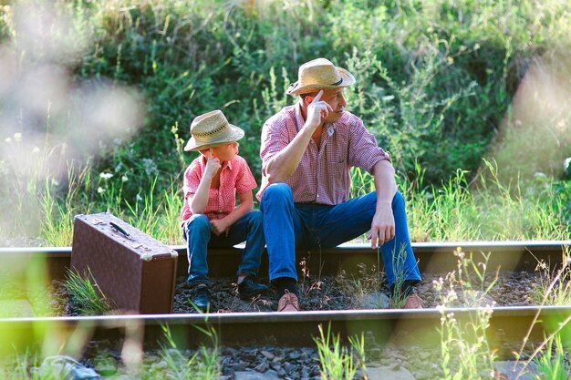 Vader en zoon cowboys wachten samen op een treinconcept geluk