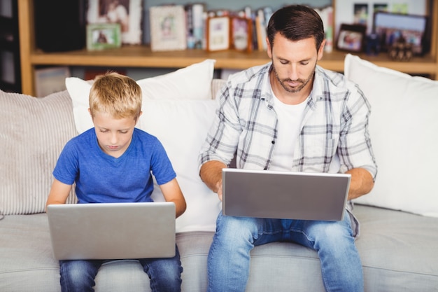 Vader en zoon die aan laptop bij bank werken