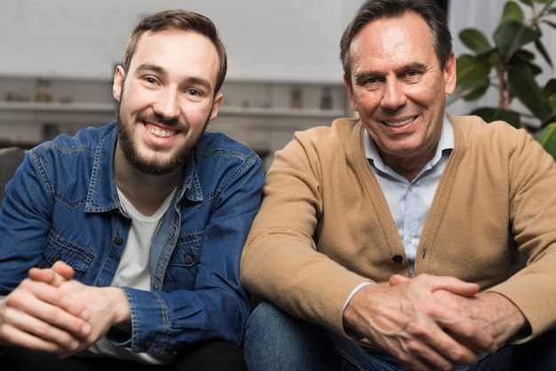 Foto vader en zoon die en in woonkamer glimlachen stellen