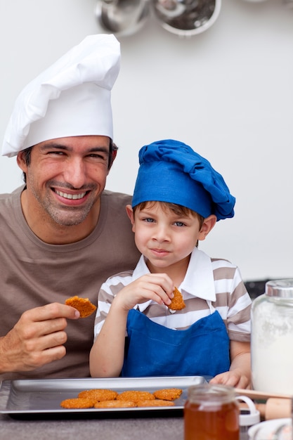 Vader en zoon die koekjes in de keuken eten