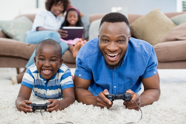 Vader en zoon die op deken liggen en videospelletje spelen