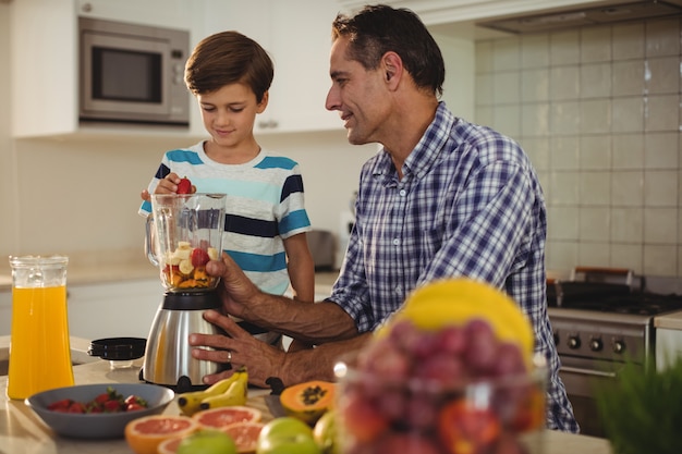 Vader en zoon die smoothie in keuken voorbereiden