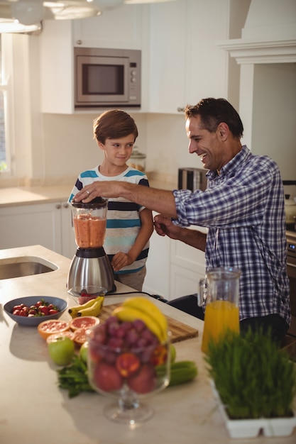 Vader en zoon die smoothie in keuken voorbereiden