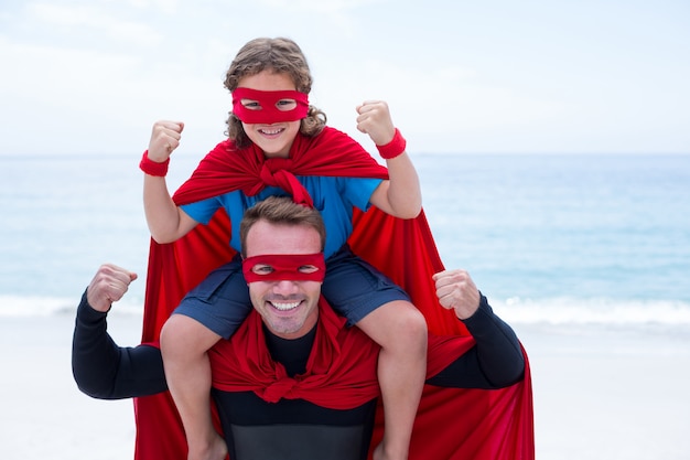 Vader en zoon die terwijl het buigen van spieren op zee kust glimlachen