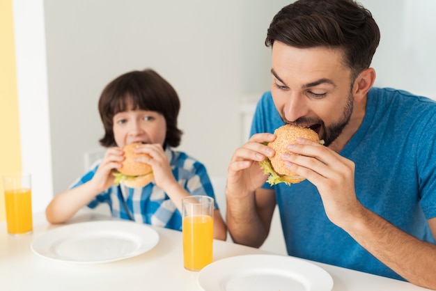 Vader en zoon eten een hamburger met sap.