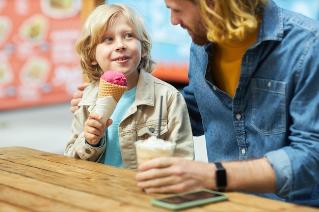 Vader en zoon eten ijs en genieten van een band