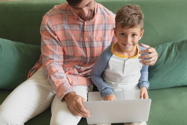 Foto vader en zoon gebruiken een laptop in de woonkamer.