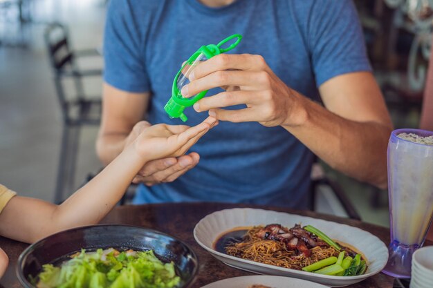 Vader en zoon gebruiken handdesinfecterende gel voor het eten in een café