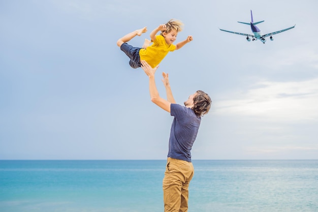 Vader en zoon hebben plezier op het strand en kijken naar de landende vliegtuigen Reizen met een vliegtuig met kinderen concept