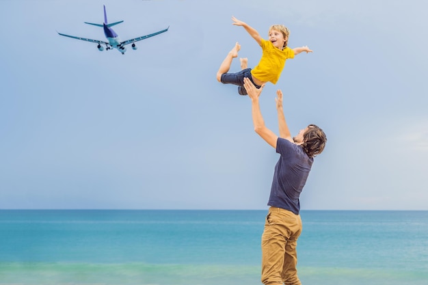 Vader en zoon hebben plezier op het strand en kijken naar de landende vliegtuigen Reizen met een vliegtuig met kinderen concept