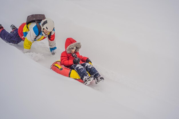 Vader en zoon hebben plezier op tubing in de winter Winterpret voor het hele gezin