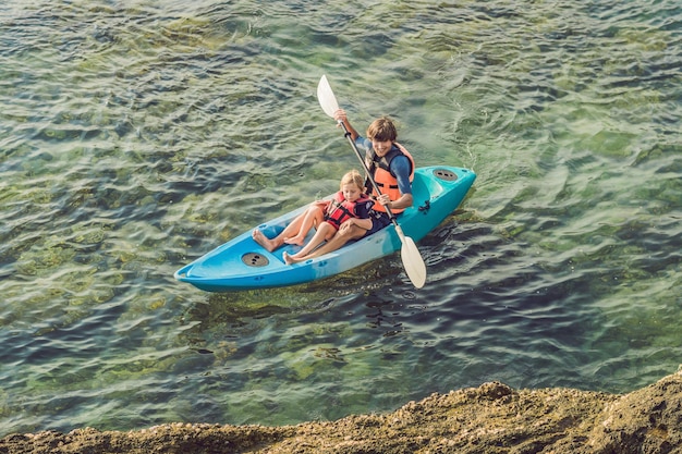 Vader en zoon kajakken op tropische oceaan.