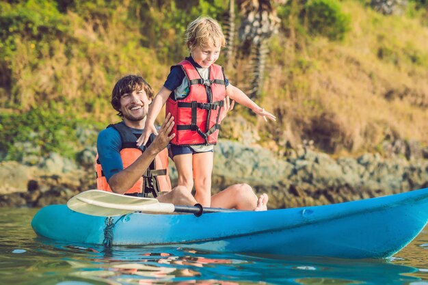 Vader en zoon kajakken op tropische oceaan.