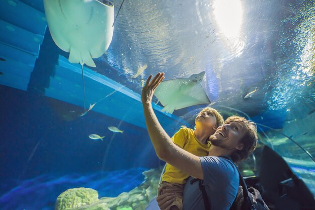 Foto vader en zoon kijken naar vissen in een tunnelaquarium