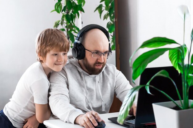 Vader en zoon lachen plezier, spelen thuis een videogame op laptop, brengen samen tijd door