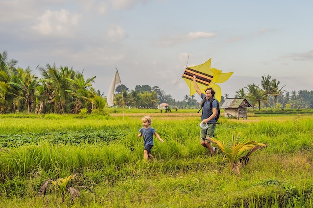 Vader en zoon lanceren een vlieger in een rijstveld in Ubud, Bali, Indonesië