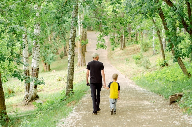 Vader en zoon lopen in het park. Vader en kind in de natuur. alleenstaande ouder in het gezin. vaderdag met kinderen.