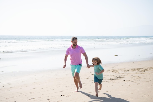 Vader en zoon lopen op het strand van de zomer. familie reizen weekend en vakantie. vaderdag of familiedag. papa met jongen jongen op zomerdag. vader en kind plezier buitenshuis. jeugd en ouderschap.