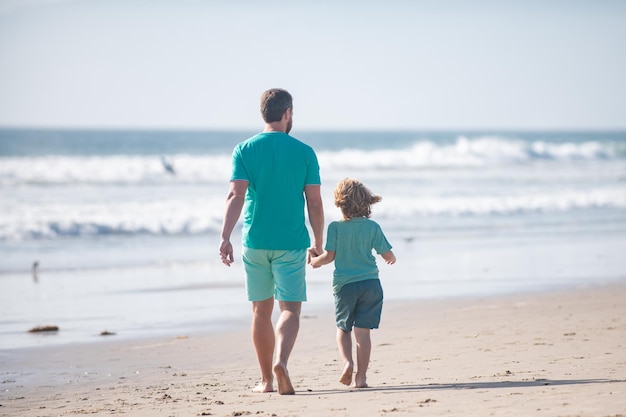 Vader en zoon lopen op zee vader en kind hand in hand en lopen samen