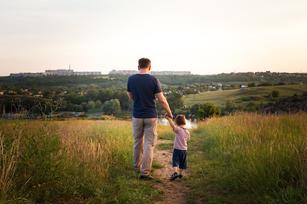 Vader en zoon lopen 's avonds in een geel zomerveld