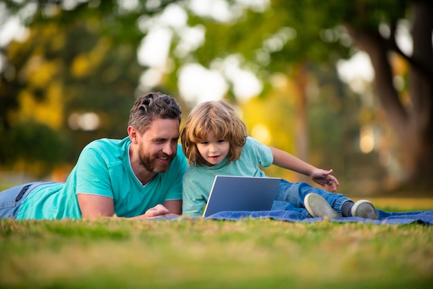 Vader en zoon met een laptop op de natuur in het park