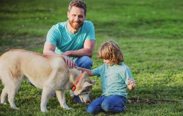 Vader en zoon met hond ontspannen op de natuur in het park