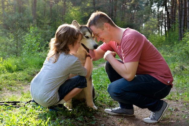 Vader en zoon met hun hond malamute op een wandeling in het bos