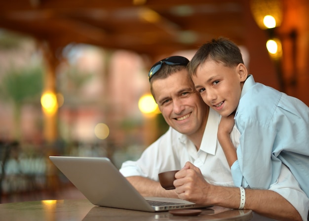 Vader en zoon met laptop aan tafel