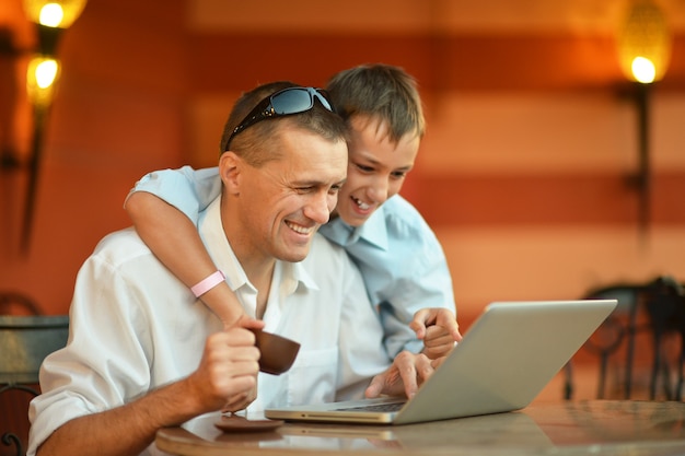 Vader en zoon met laptop aan tafel