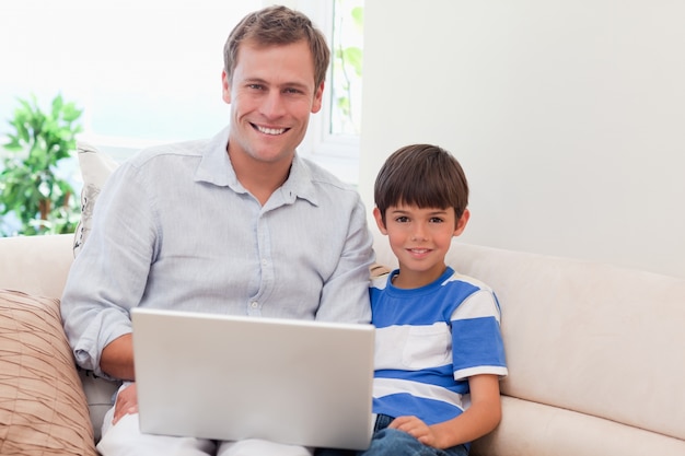 Vader en zoon met laptop op de bank