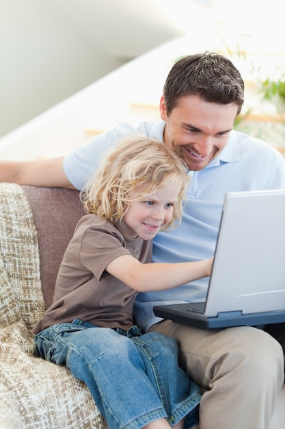 Vader en zoon met laptop op sofa