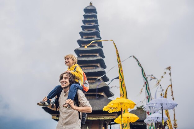 Vader en zoon op de achtergrond van Pura Ulun Danu Bratan, Bali. Hindoese tempel omringd door bloemen op Bratan-meer, Bali. Grote Shivaite-watertempel in Bali, Indonesië. hindoe tempel. Op reis met kinderen