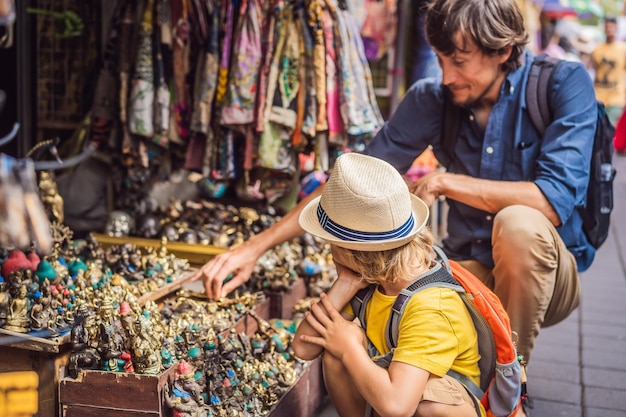 Vader en zoon op een markt in Ubud Bali Typische souvenirwinkel met souvenirs en handwerk van Bali op de beroemde markt van Ubud, Indonesië Balinese markt Souvenirs van hout en ambachten van lokale