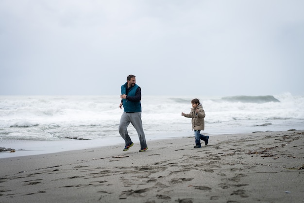 Vader en zoon plezier op winter strand