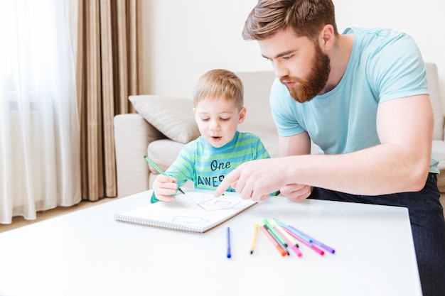 Vader en zoon praten en tekenen samen thuis