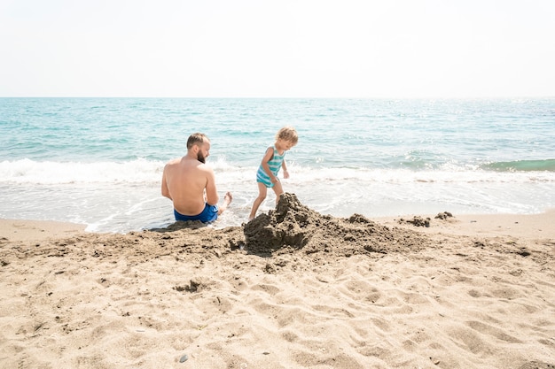 Vader en zoon rennen samen naar de oceaan tijdens de zomervakantie