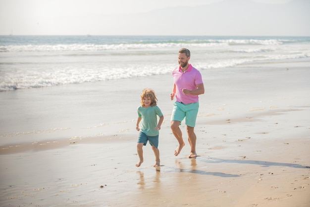 Vader en zoon rennen samen op zomerstrand samen saamhorigheid