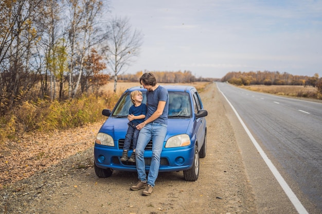 Vader en zoon rusten aan de kant van de weg tijdens een roadtrip. Road trip met kinderen concept.