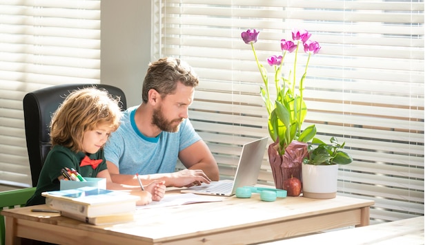 Vader en zoon schrijven en gebruiken computer thuis. familie blog. jongen doe huiswerk