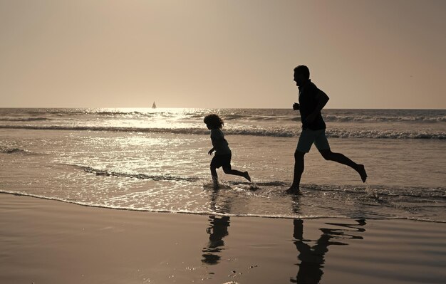 Vader en zoon silhouetten rennen met plezier en voelen vrijheid op zomerstrandfamilie