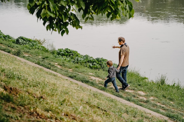 Vader en zoon spelen aan de oever van de rivier in het park