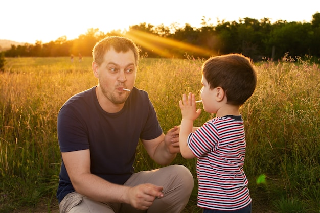 Vader en zoon spelen buiten in een veld bij zonsondergang.