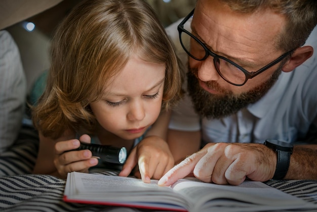 Vader en zoon spelen en lezen in een kindertent thuis