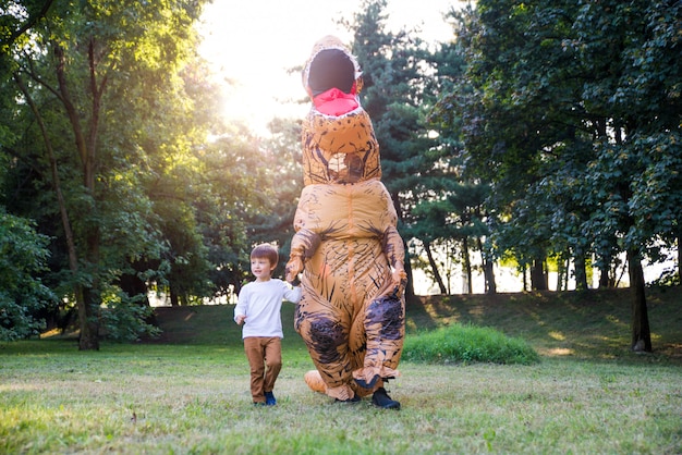 Vader en zoon spelen in het park, met een dinosaurus kostuum, plezier maken met het gezin buiten