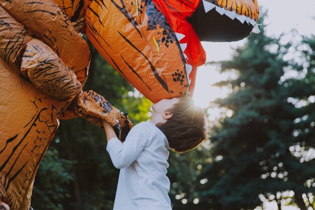 Vader en zoon spelen in het park, met een dinosaurus kostuum, plezier maken met het gezin buiten
