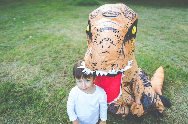 Vader en zoon spelen in het park, met een dinosaurus kostuum, plezier maken met het gezin buiten